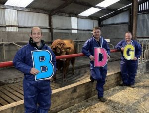 Three farmers holding the letters B, D and G
